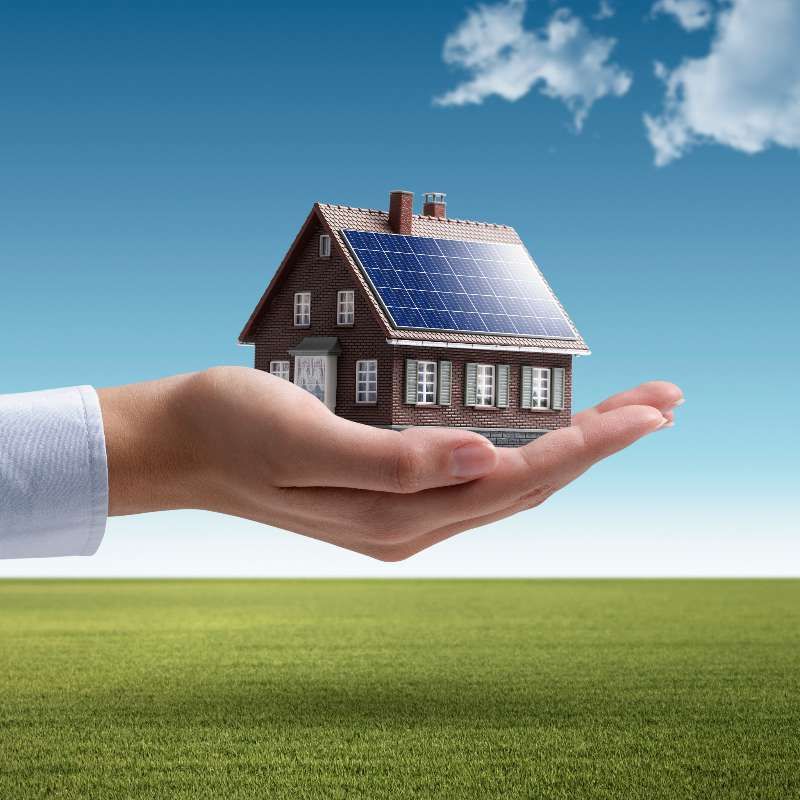 Mano sosteniendo casa con paneles solares